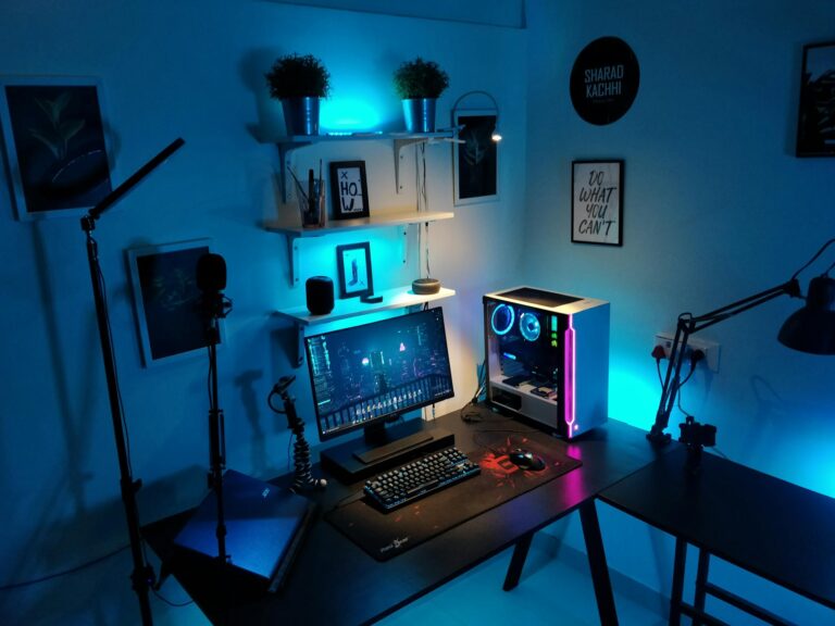 A sleek computer setup in a studio with blue ambient lighting and tech equipment.