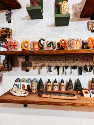 Artisan crafts displayed on wooden shelves in a cozy, colorful workshop.
